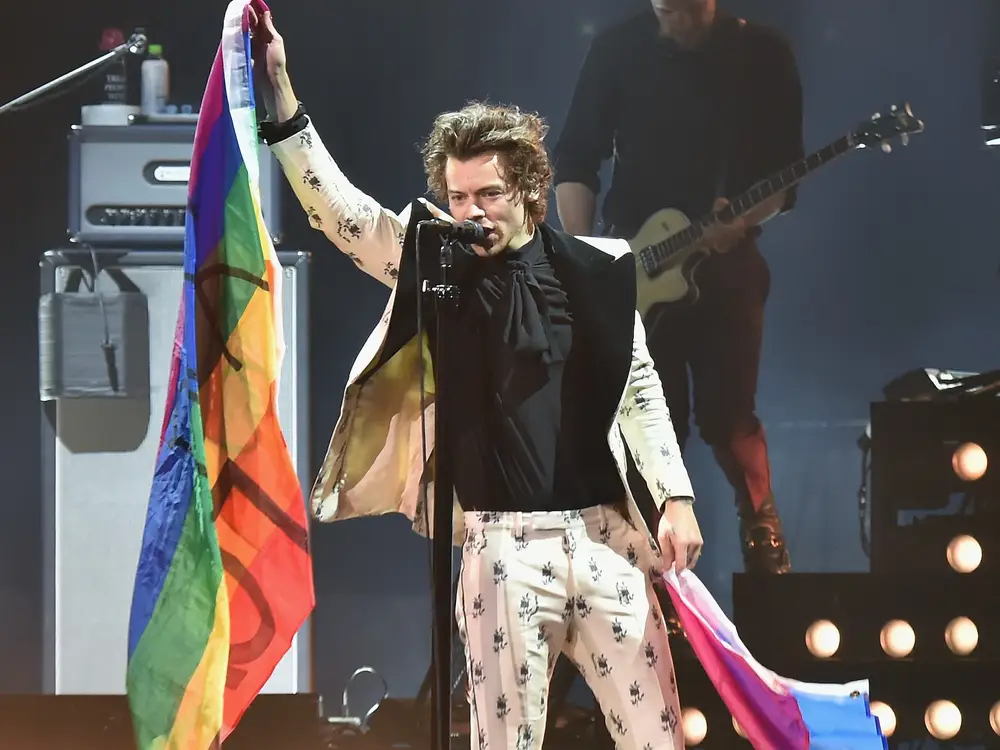 Harry Styles with a Pride flag and a Bi flag