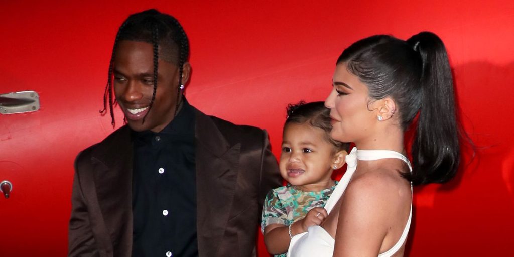 Travis Scott and Kylie Jenner posing while holding their second child